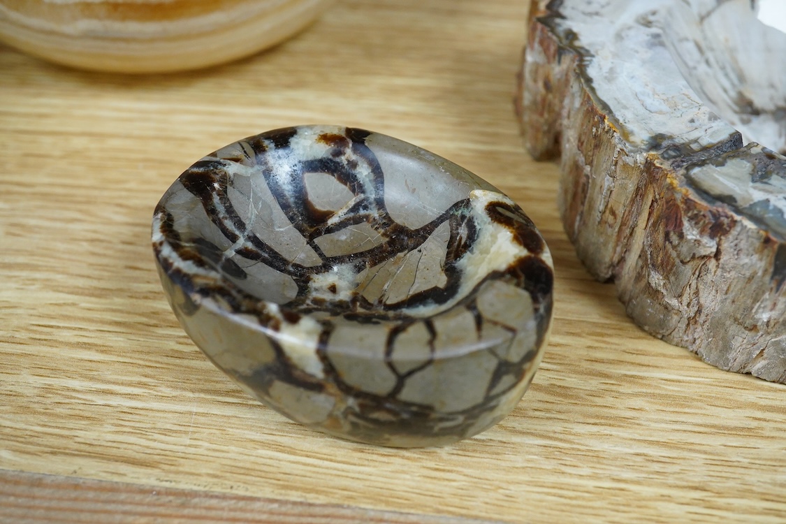 Two petrified wood ashtrays, a malachite rock, three onyx bowls, one with cover, and one other item, larger ashtray 17.5cm wide